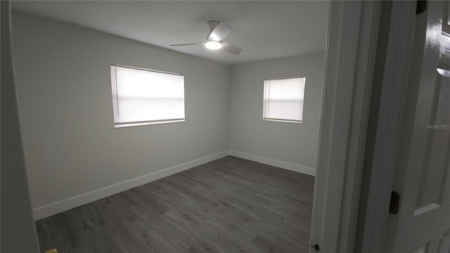 unfurnished room with dark wood-style floors, a ceiling fan, a wealth of natural light, and baseboards