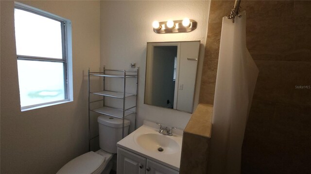 bathroom featuring a shower with shower curtain, vanity, and toilet