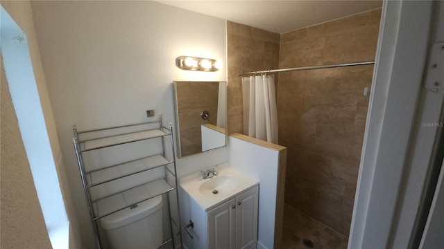 bathroom featuring toilet, a tile shower, and vanity