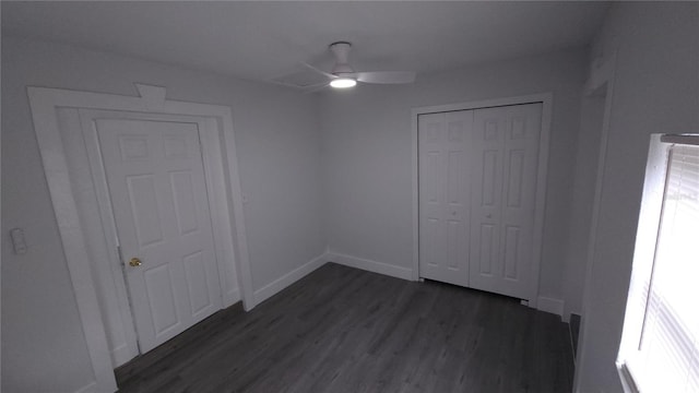 unfurnished bedroom featuring ceiling fan, baseboards, dark wood finished floors, and a closet