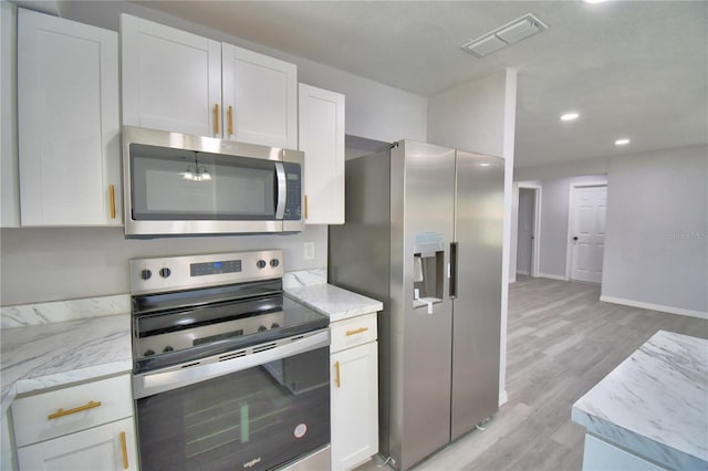 kitchen featuring white cabinetry, light stone counters, stainless steel appliances, and light hardwood / wood-style floors