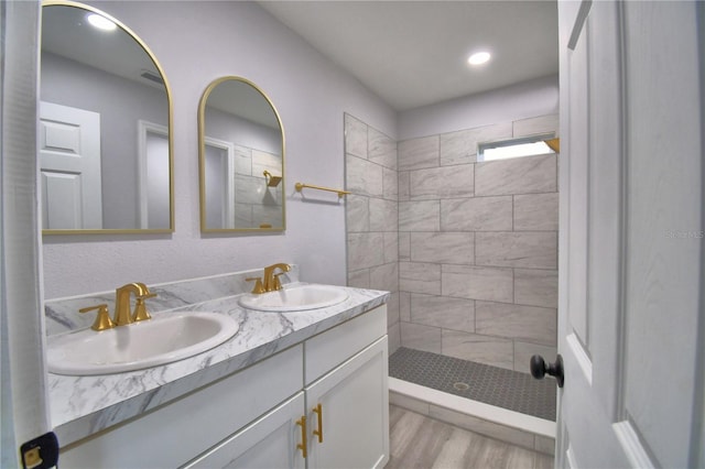 bathroom with a tile shower, hardwood / wood-style floors, and vanity