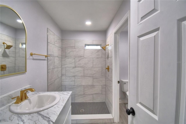 bathroom featuring vanity, toilet, and a tile shower