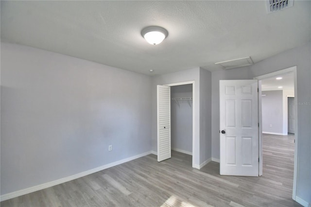 unfurnished bedroom featuring light hardwood / wood-style floors, a closet, and a textured ceiling