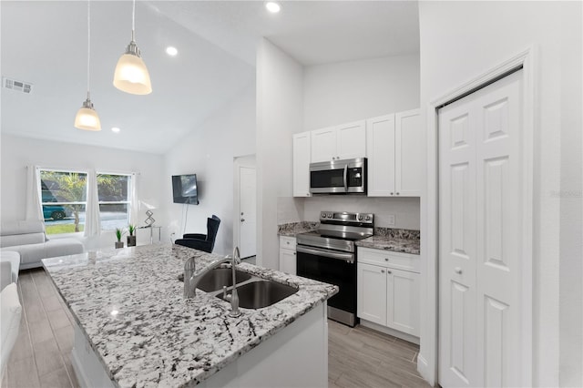 kitchen with appliances with stainless steel finishes, sink, hanging light fixtures, and white cabinets