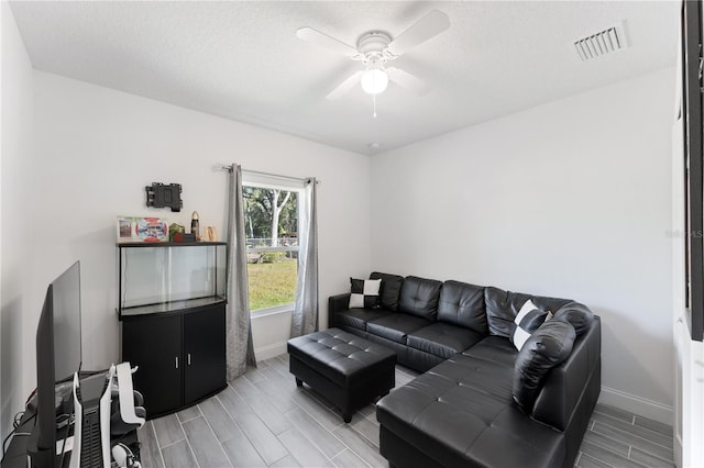 living room featuring ceiling fan and a textured ceiling