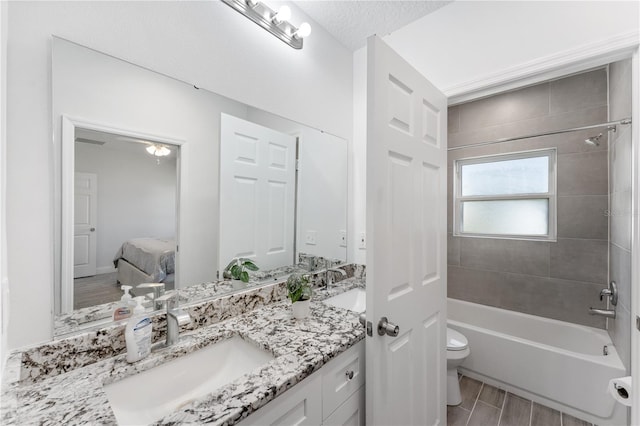 full bathroom featuring vanity, tiled shower / bath combo, a textured ceiling, and toilet