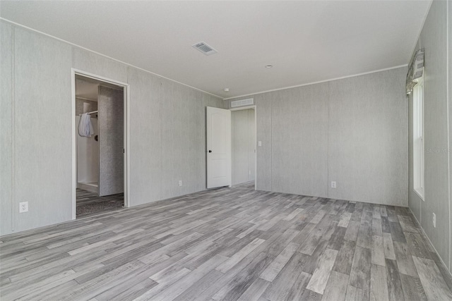 empty room with crown molding and light wood-type flooring