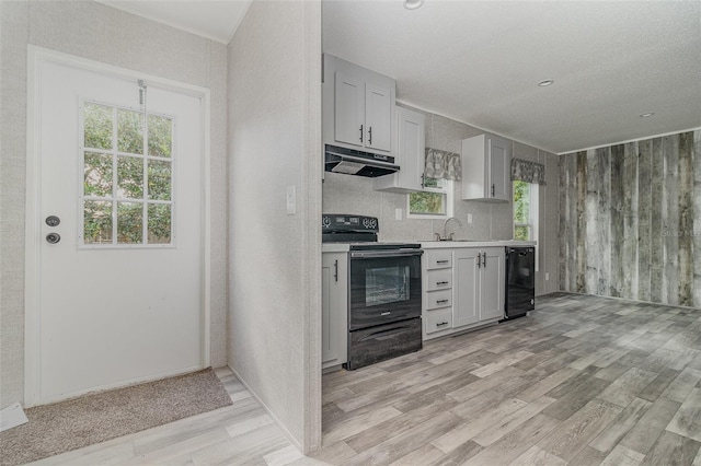 kitchen with black / electric stove, beverage cooler, sink, and light wood-type flooring