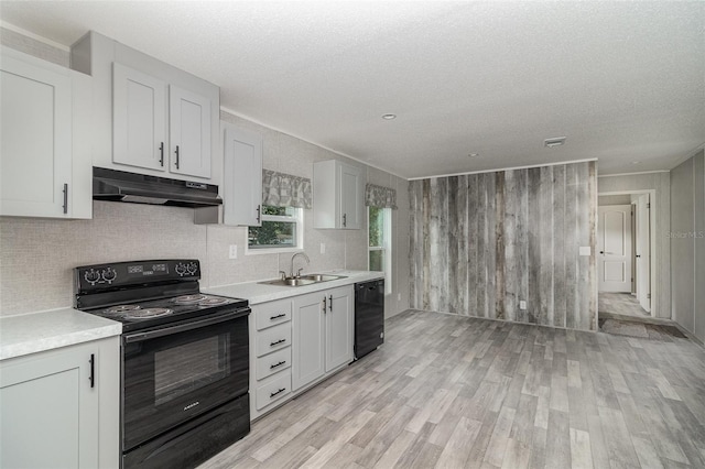 kitchen featuring black electric range oven, sink, white cabinetry, beverage cooler, and light wood-type flooring