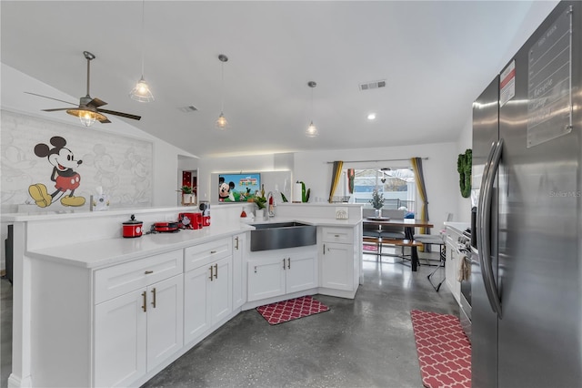 kitchen with vaulted ceiling, sink, white cabinets, stainless steel fridge, and hanging light fixtures