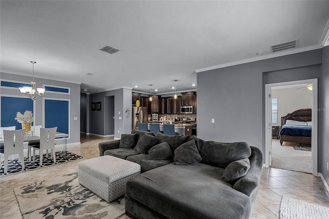 living room with a textured ceiling, ornamental molding, a chandelier, and light tile patterned flooring