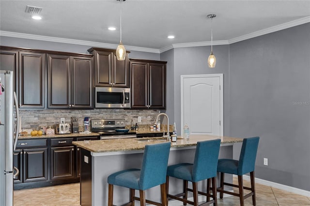 kitchen with appliances with stainless steel finishes, sink, a kitchen island with sink, and hanging light fixtures