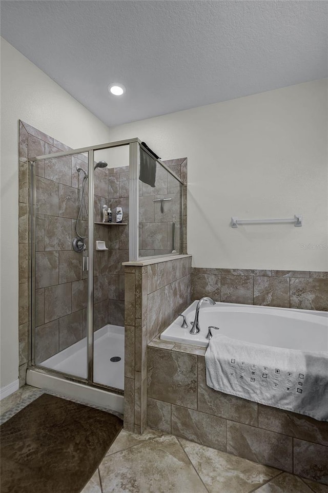 bathroom with a textured ceiling and separate shower and tub