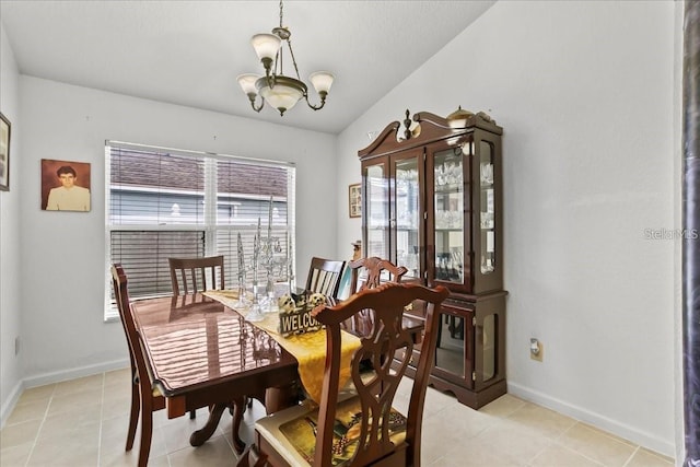 tiled dining room featuring an inviting chandelier and lofted ceiling