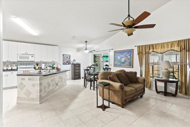 living room with ceiling fan, light tile patterned floors, vaulted ceiling, and a textured ceiling