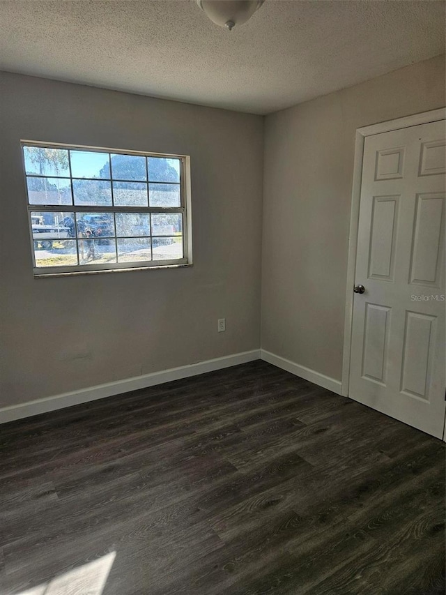 spare room featuring a textured ceiling and dark hardwood / wood-style flooring