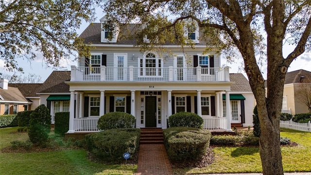 view of front of home with a balcony and a front yard