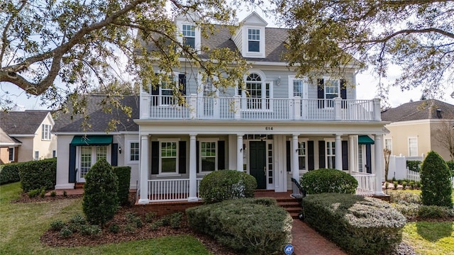 new england style home with a balcony and covered porch