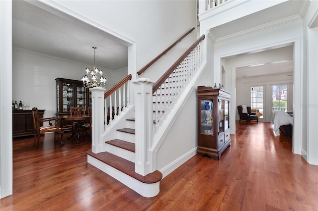 stairway with crown molding, a notable chandelier, and hardwood / wood-style flooring