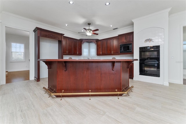 kitchen with ornamental molding, a breakfast bar, a kitchen island, and black appliances