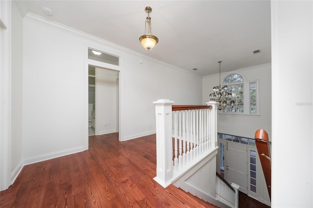 hall with ornamental molding, dark wood-type flooring, and a chandelier