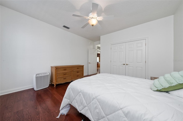 bedroom featuring dark hardwood / wood-style floors, a textured ceiling, ceiling fan, and a closet