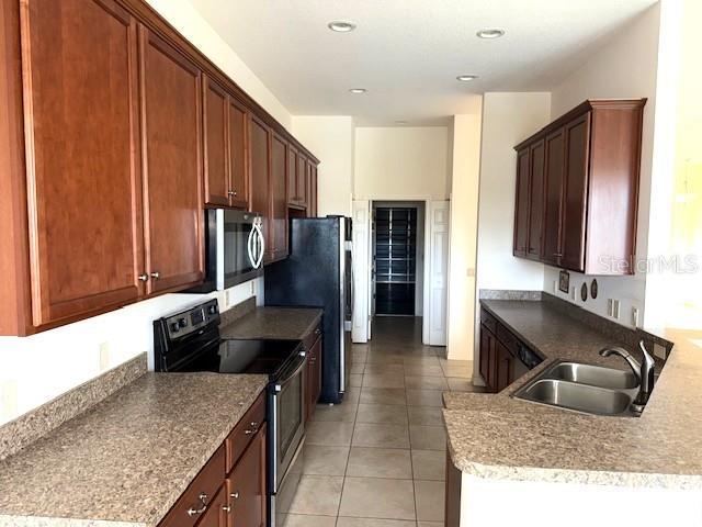 kitchen with appliances with stainless steel finishes, sink, and light tile patterned floors