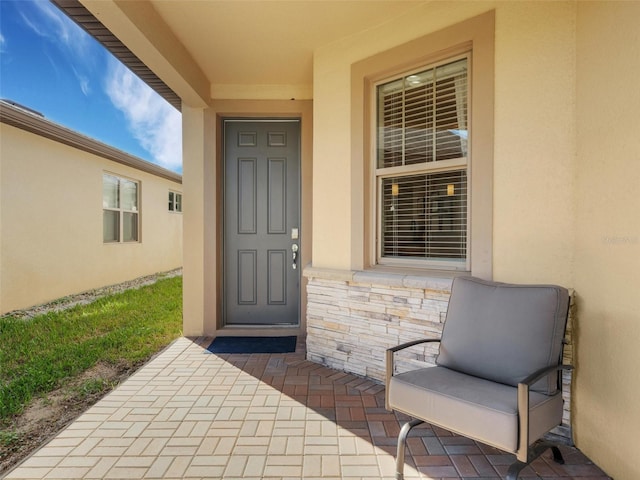 doorway to property with stone siding and stucco siding