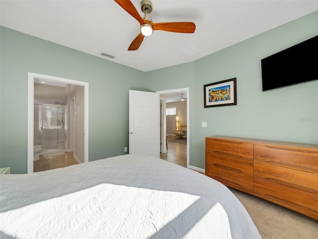 carpeted bedroom with connected bathroom, visible vents, and a ceiling fan