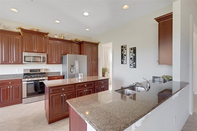 kitchen with appliances with stainless steel finishes, a kitchen island, sink, and light stone countertops