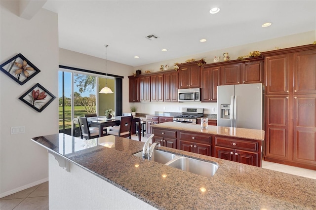 kitchen with sink, a kitchen island with sink, light tile patterned flooring, and stainless steel appliances