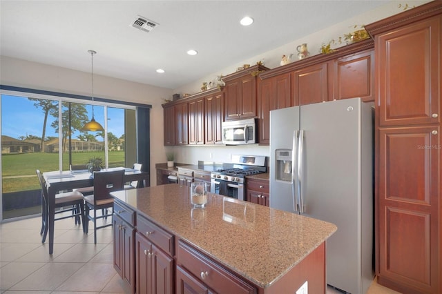 kitchen with light tile patterned floors, a center island, pendant lighting, stainless steel appliances, and light stone countertops