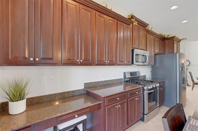 kitchen featuring dark stone countertops, appliances with stainless steel finishes, and light tile patterned floors