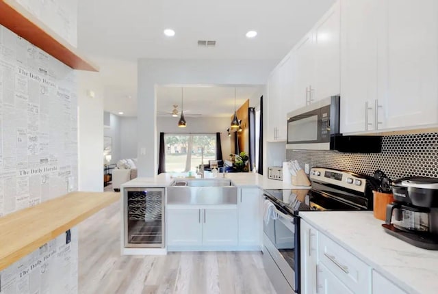 kitchen featuring appliances with stainless steel finishes, sink, wine cooler, and white cabinets