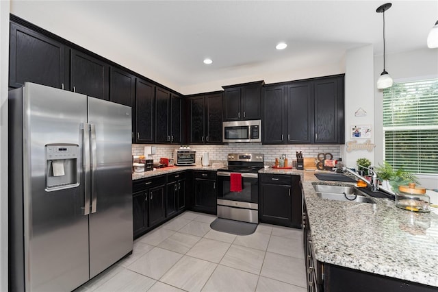 kitchen with decorative backsplash, appliances with stainless steel finishes, sink, and hanging light fixtures