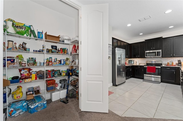 kitchen with appliances with stainless steel finishes, light tile patterned floors, and backsplash