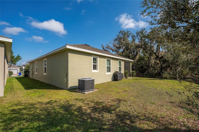 rear view of property with central AC and a lawn