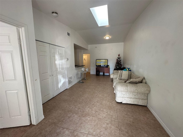 living area featuring lofted ceiling with skylight and light tile patterned floors