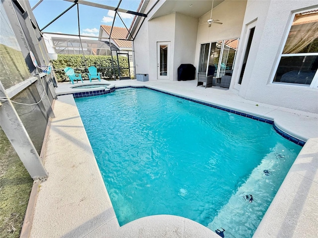 view of pool featuring a patio area, glass enclosure, ceiling fan, and an in ground hot tub