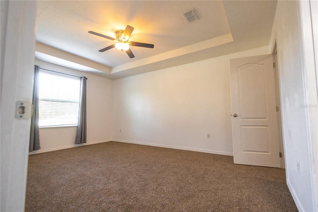 carpeted spare room featuring a raised ceiling and ceiling fan