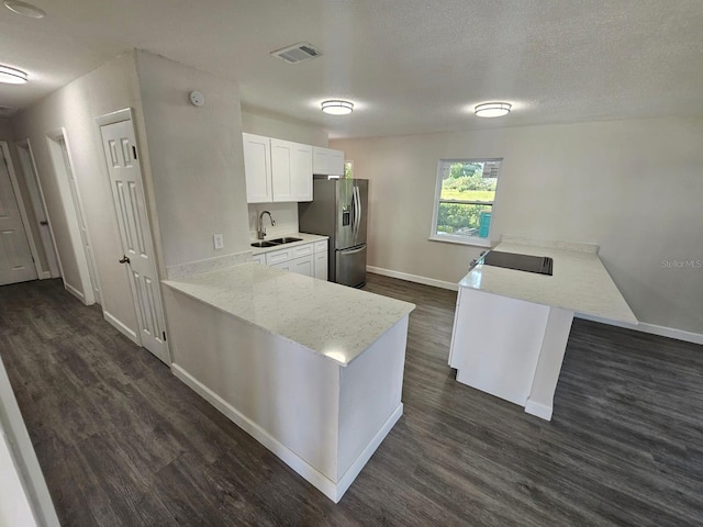 kitchen with dark wood-type flooring, stainless steel refrigerator with ice dispenser, light stone counters, white cabinets, and kitchen peninsula