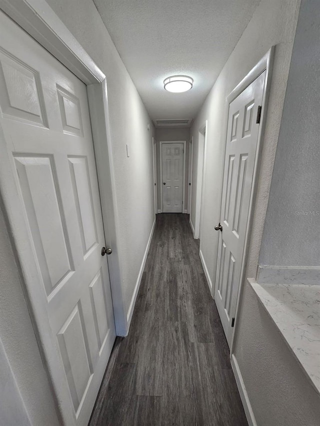 hallway featuring dark hardwood / wood-style flooring and a textured ceiling