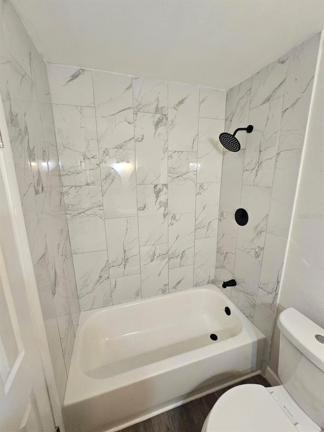 bathroom featuring tiled shower / bath combo and toilet