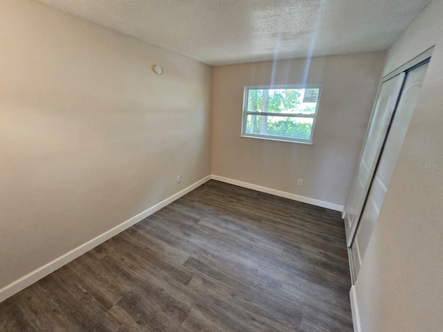 unfurnished dining area featuring dark hardwood / wood-style floors and a textured ceiling