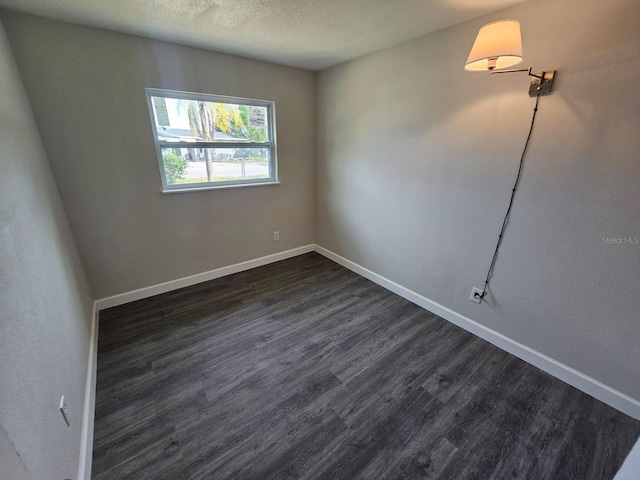 empty room with a textured ceiling and dark hardwood / wood-style flooring