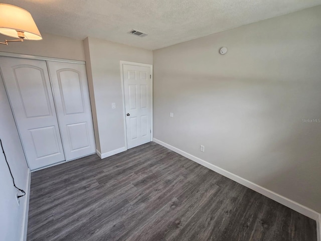 unfurnished bedroom featuring dark hardwood / wood-style flooring, a closet, and a textured ceiling