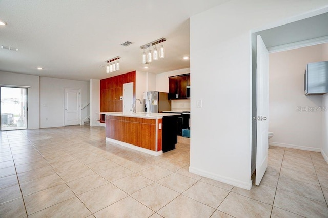 kitchen featuring sink, hanging light fixtures, light tile patterned floors, stainless steel fridge with ice dispenser, and a center island with sink