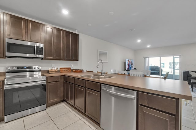 kitchen with sink, light tile patterned floors, kitchen peninsula, and appliances with stainless steel finishes