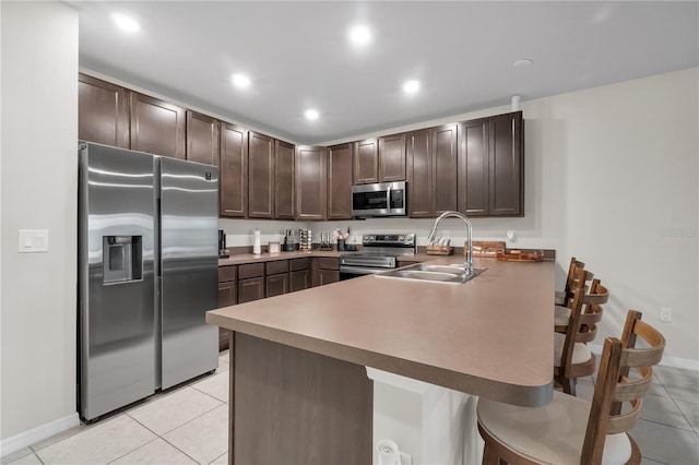 kitchen featuring sink, a breakfast bar area, dark brown cabinets, stainless steel appliances, and kitchen peninsula